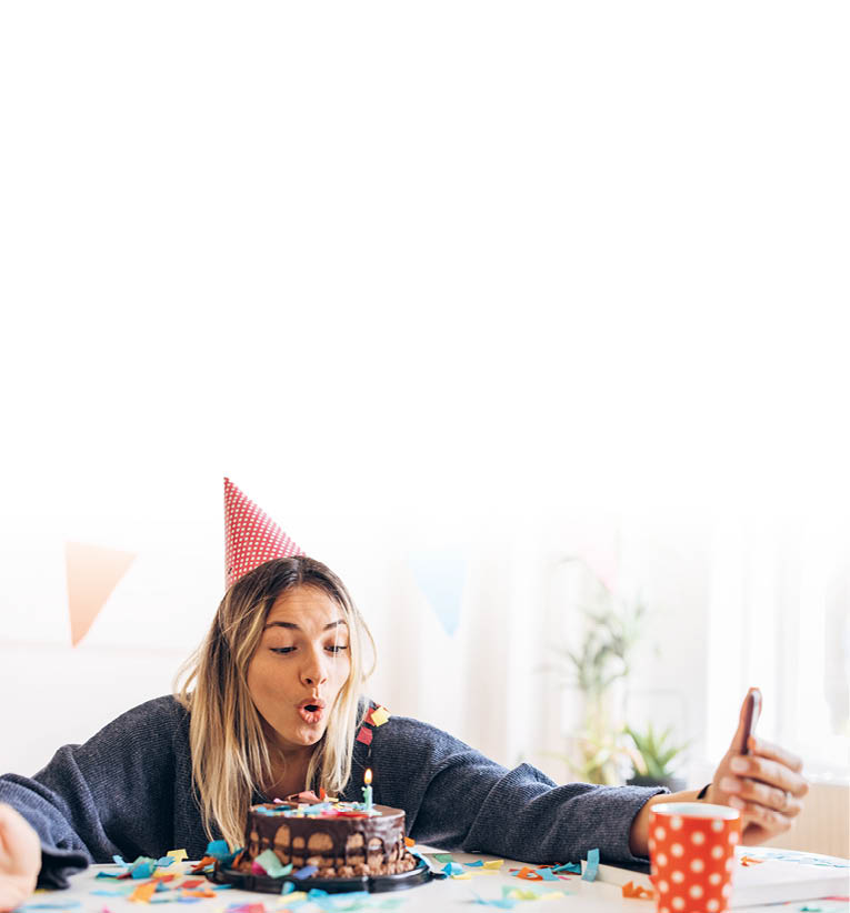 One woman, beautiful young woman using smart phone for selfie, she is celebrating her birthday alone at home.