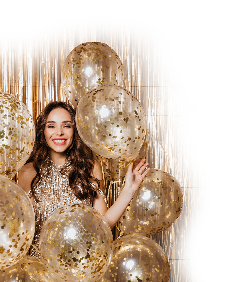 Beautiful lady in shiny top is laughing and posing with balloons on gold background