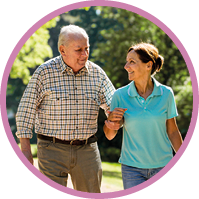 Caregiver – woman with senior man outdoors in the park