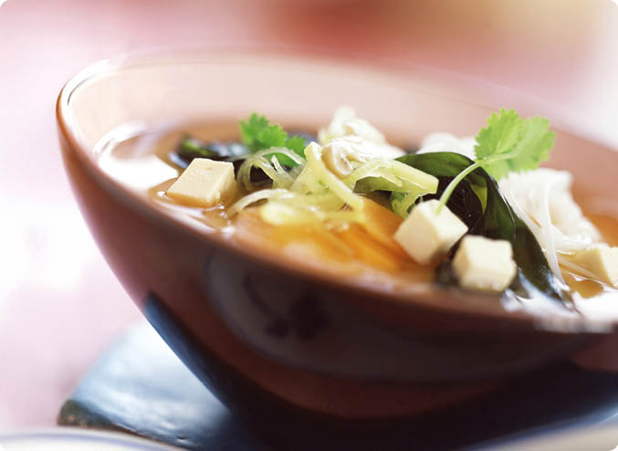 Schale mit klarer Suppe, darin Tofuw rfel, gr ne Kr uter und d nne Gem sestreifen