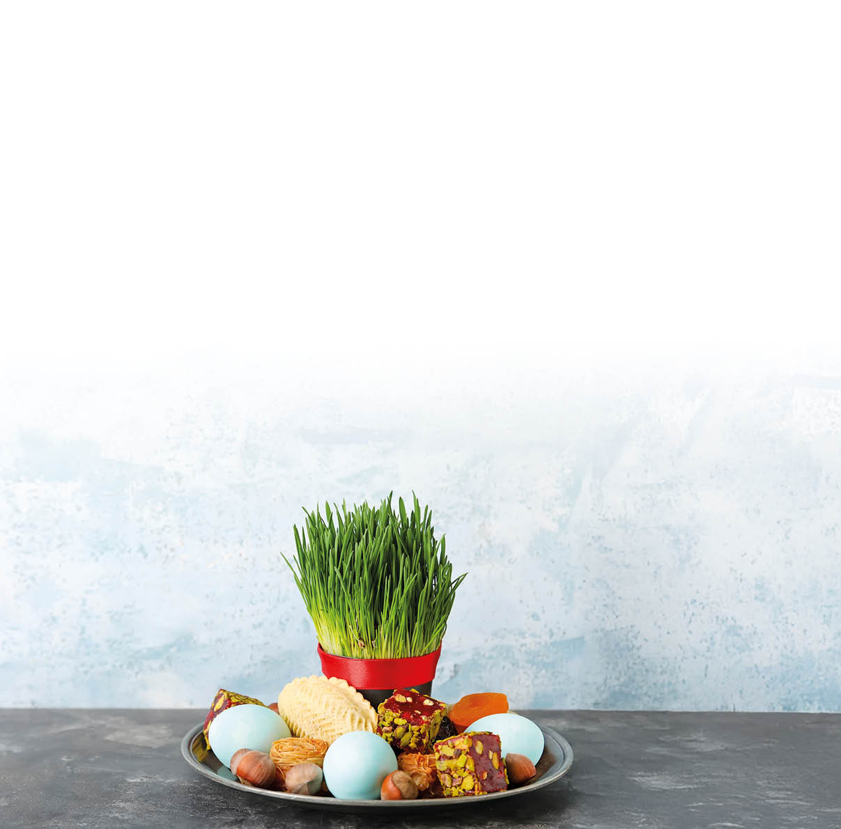 Green wheat grass with eggs and sweets for Novruz Bayram on grunge background with space for text.