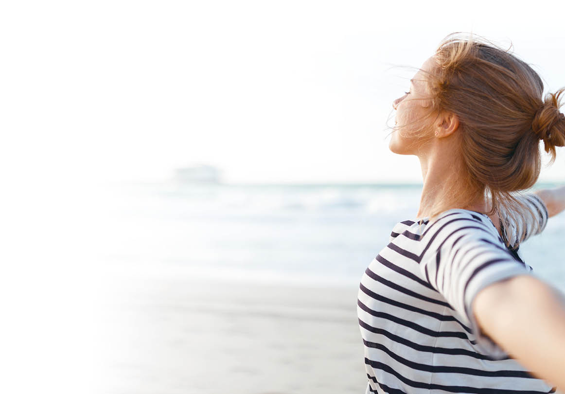 happy young woman enjoying freedom with open hands on sea 