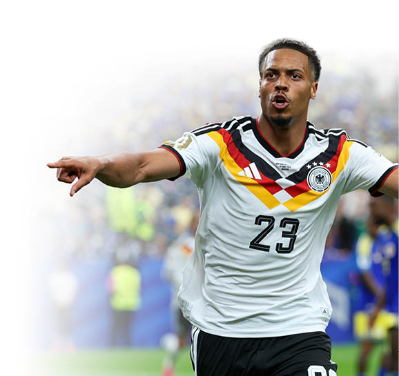Eine Person in einem Fu balltrikot mit der Nummer 23 feiert mit ausgestreckten Armen auf einem Spielfeld, w hrend im Hintergrund weitere Spieler und Zuschauer zu sehen sind. Beschreibung von KI generiert