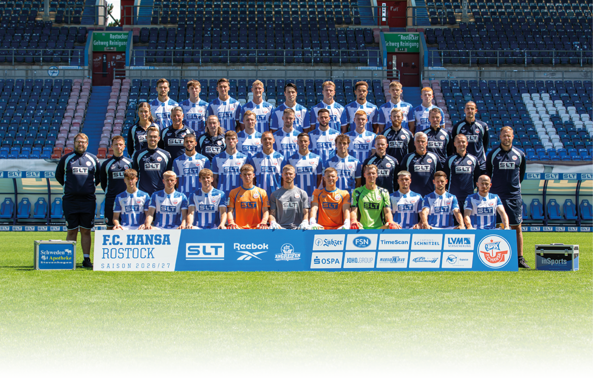 Eine gro e Gruppe von Erwachsenen in Sportkleidung posiert in mehreren Reihen auf einem Fu ballfeld vor leeren Trib nen mit einem Banner im Vordergrund, das Sponsoren und den Namen F.C. Hansa Rostock zeigt. Beschreibung von KI generiert
