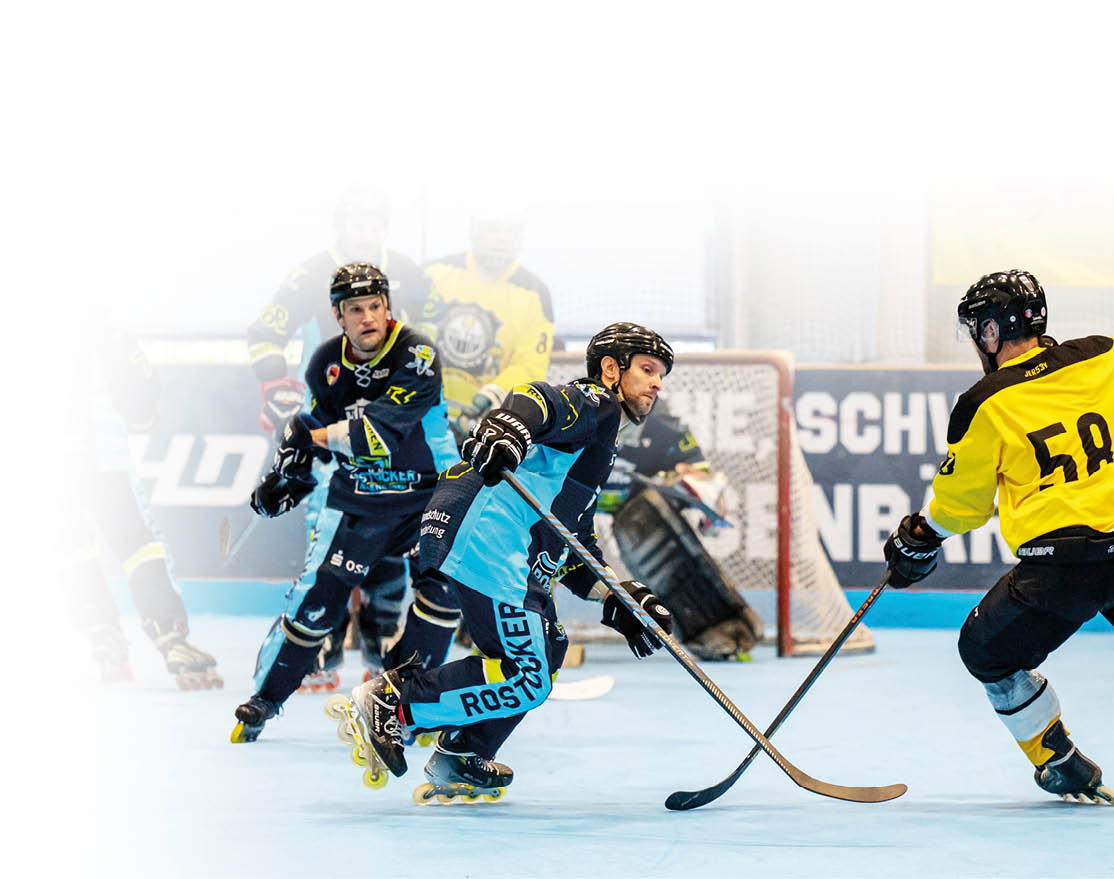 Mehrere Personen in Sportkleidung spielen auf Inline-Skates ein schnelles Hockeyspiel auf einem Hallenboden, wobei zwei Spieler aktiv um den Puck k mpfen. Beschreibung von KI generiert